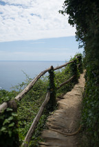 A path with a rustic railing near a lake.