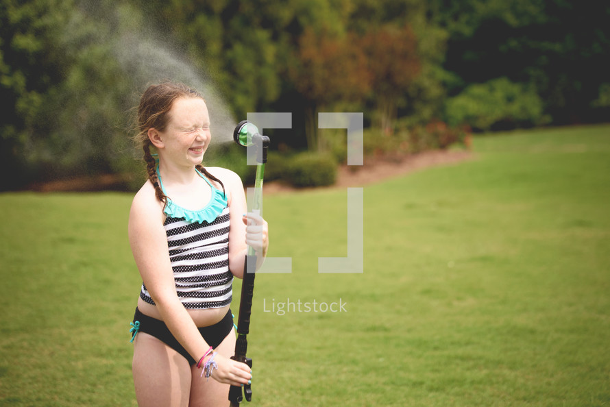 child spraying a hose on a summer day 