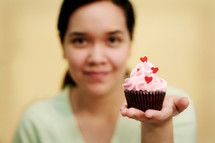 A woman holding a Valentine's cupcake 