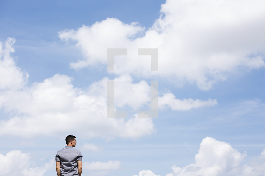 a man standing outdoors thinking with blue skies in background 