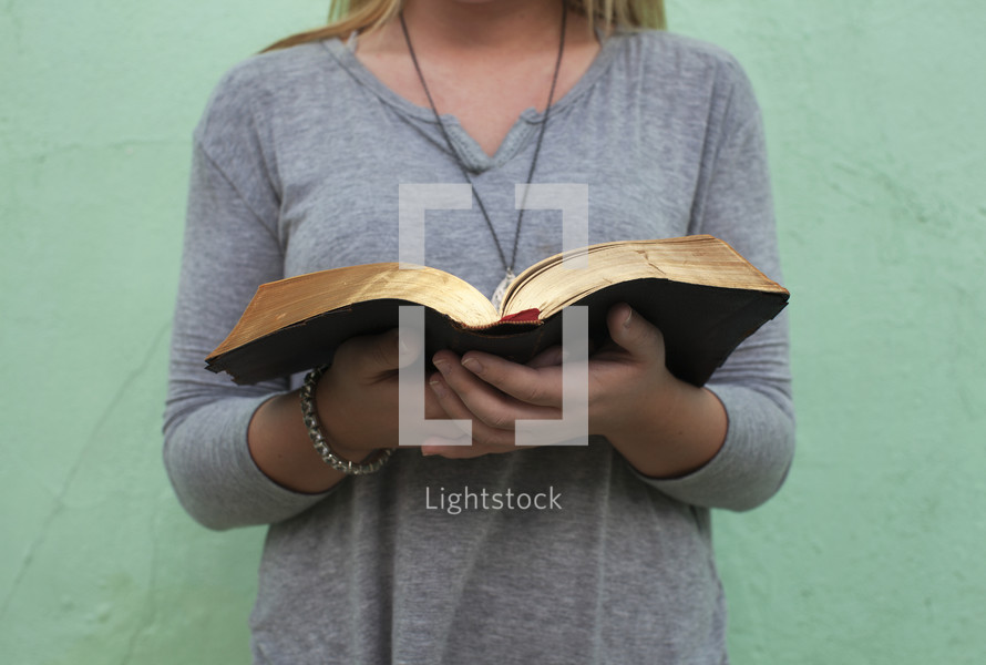 the torso of a woman holding a Bible 