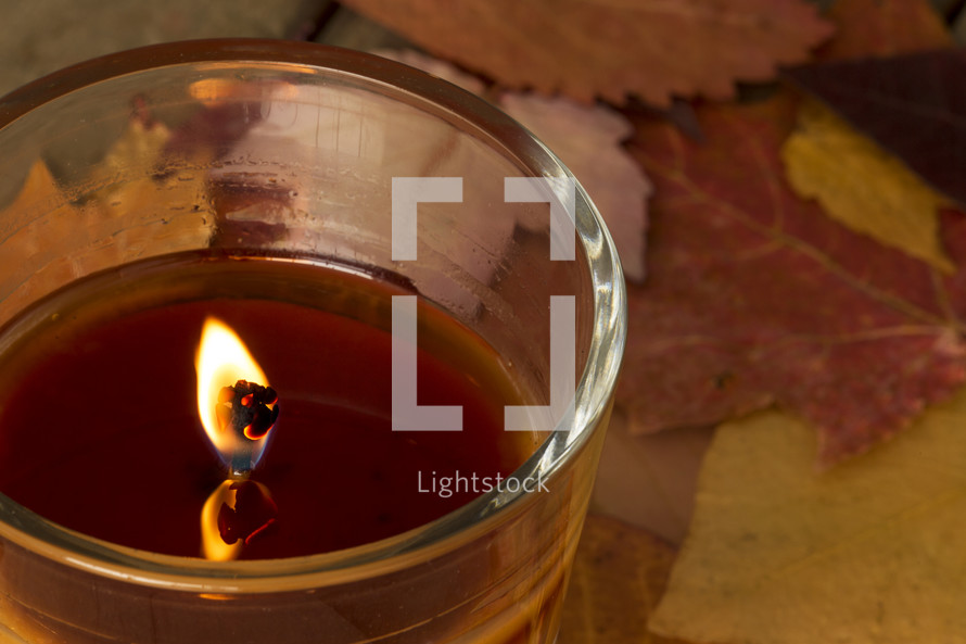 flame on a candle and fall leaves 