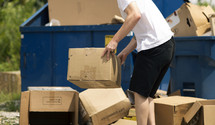 man throwing away old cardboard boxes