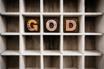 Wooden letters spelling "God" on a wooden shelf.