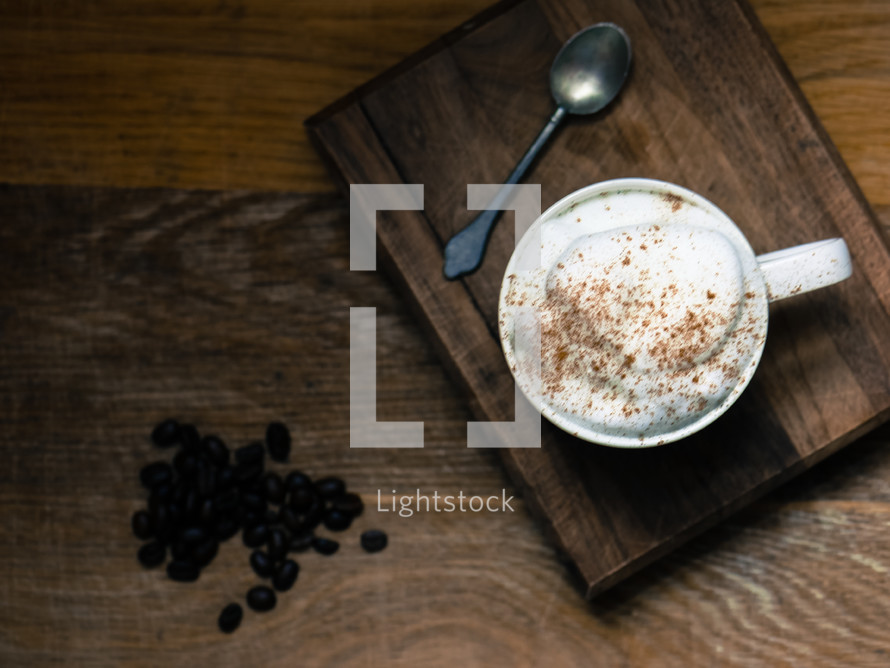 coffee beans, latte, and spoon on a wood table 
