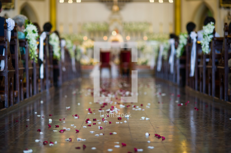 rose petals in the aisle of a church at a wedding 