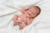 newborn in a diaper lying on a white blanket