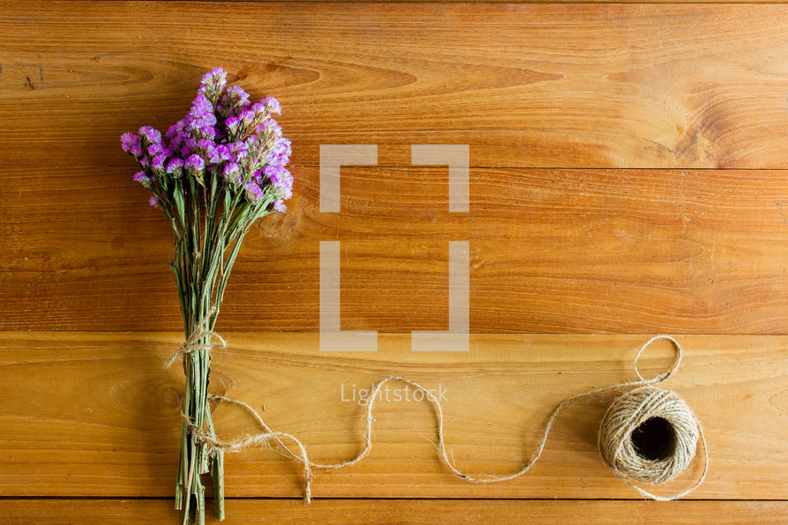 bouquet of purple flowers and twine on a wood background 