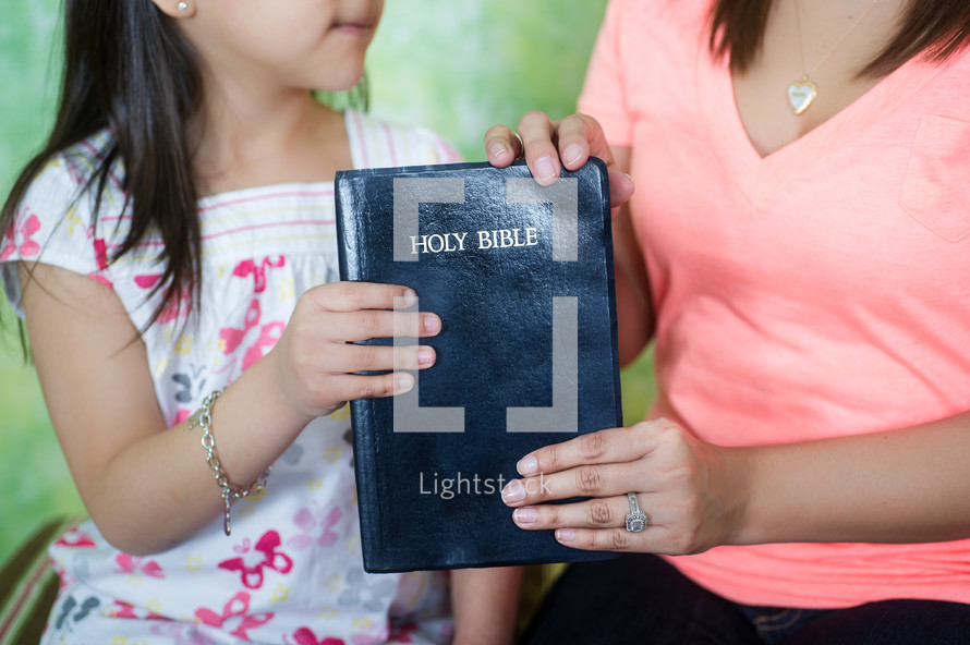 Mother handing Bible to her daughter.