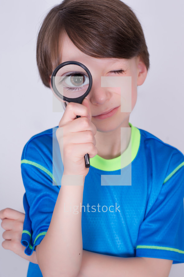Boy looking through a magnifying glass. 