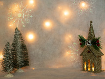 Glittery house decoration with small trees on fuzzy snow backdrop
