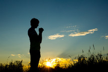 silhouette of a man with praying hands 