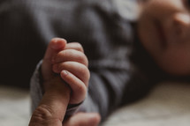 an infant grasping father's hand 
