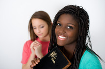 teen girls praying with Bibles
