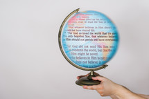 Hands holding a globe with the words of John 3:16 on it.