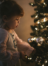 a toddler girl in front of a Christmas tree