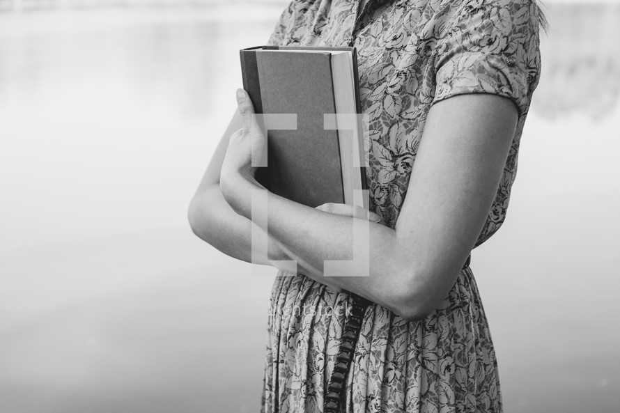 a woman holding a book against her chest 
