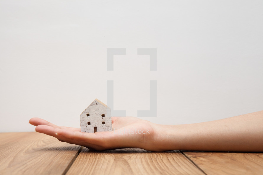 hand holding a wooden house figurine 