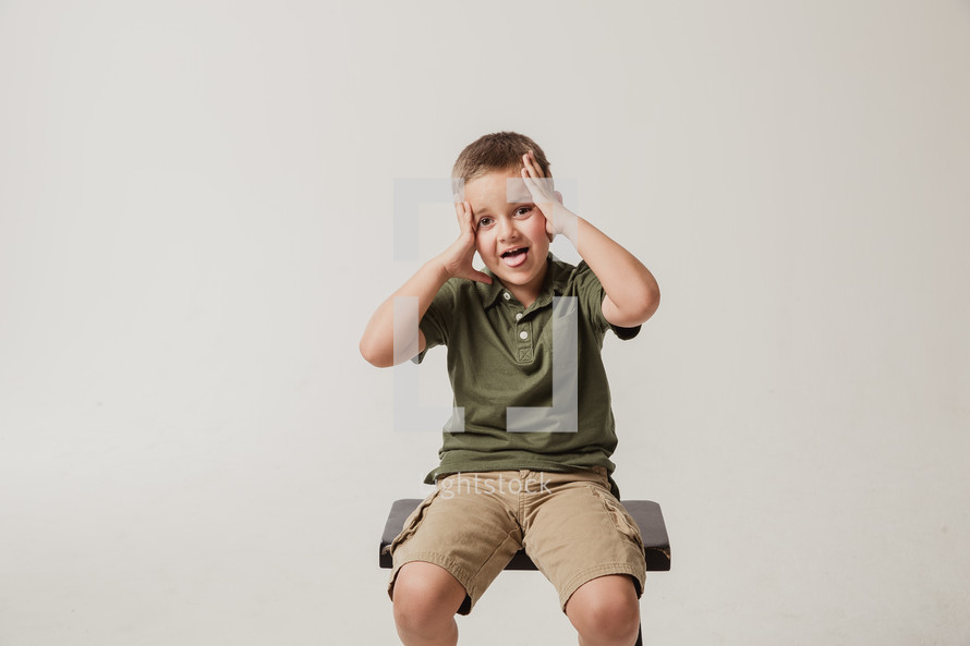 boy child sitting on a stool with his tongue out 