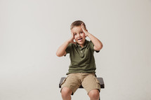 boy child sitting on a stool with his tongue out 