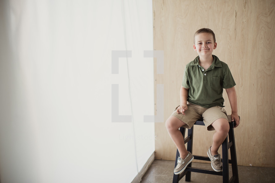 boy child sitting on a stool smiling 