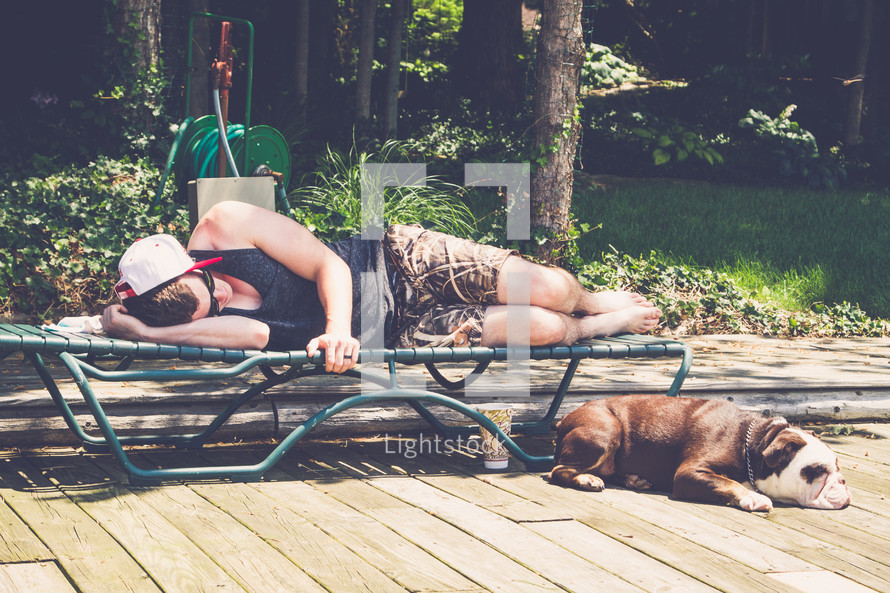 a man resting on a lounge chair next to a bulldog 