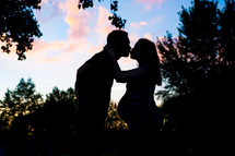 silhouette of an expecting couple kissing