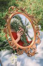 reflection in a mirror of a woman holding a bouquet of daisies 