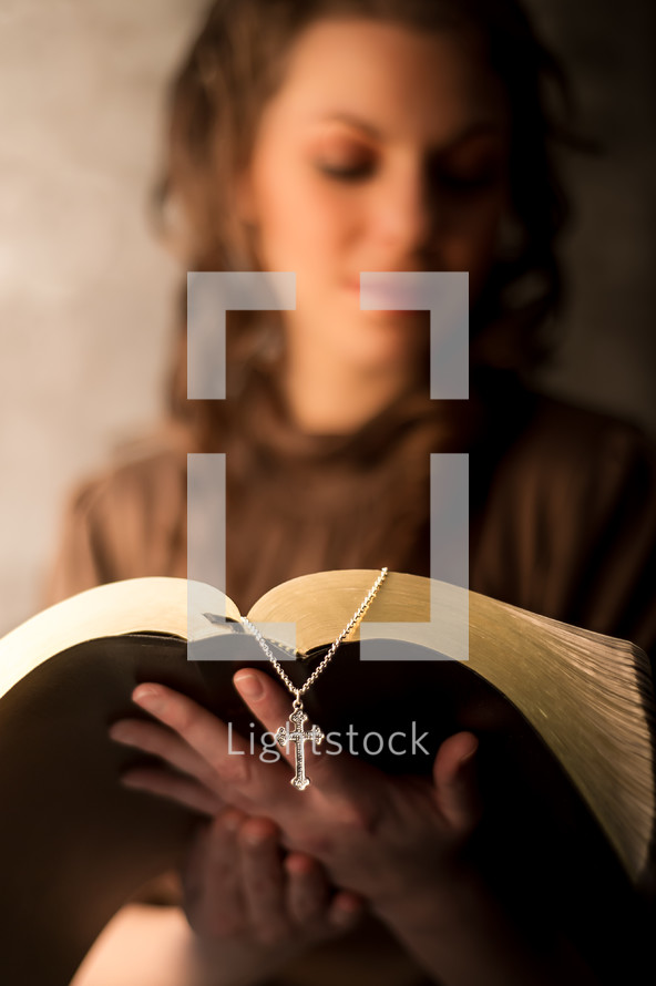 woman reading a Bible and a rosary bookmark