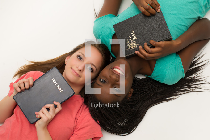 Teen girls holding Bibles against their hearts. 