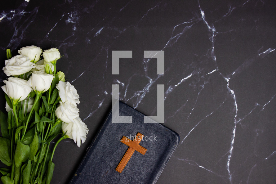 white roses and Bible on black marble background 