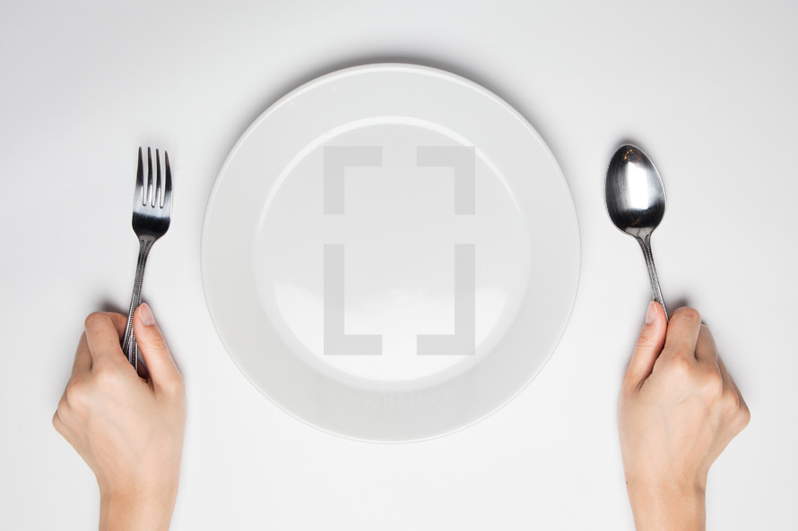 plate and hands holding a fork and spoon 