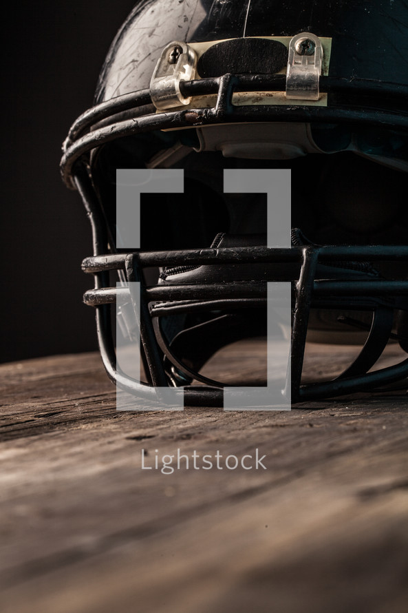 scratched up football helmet on wood 
