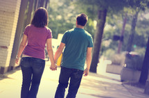 man and woman walking on a sidewalk holding hands
