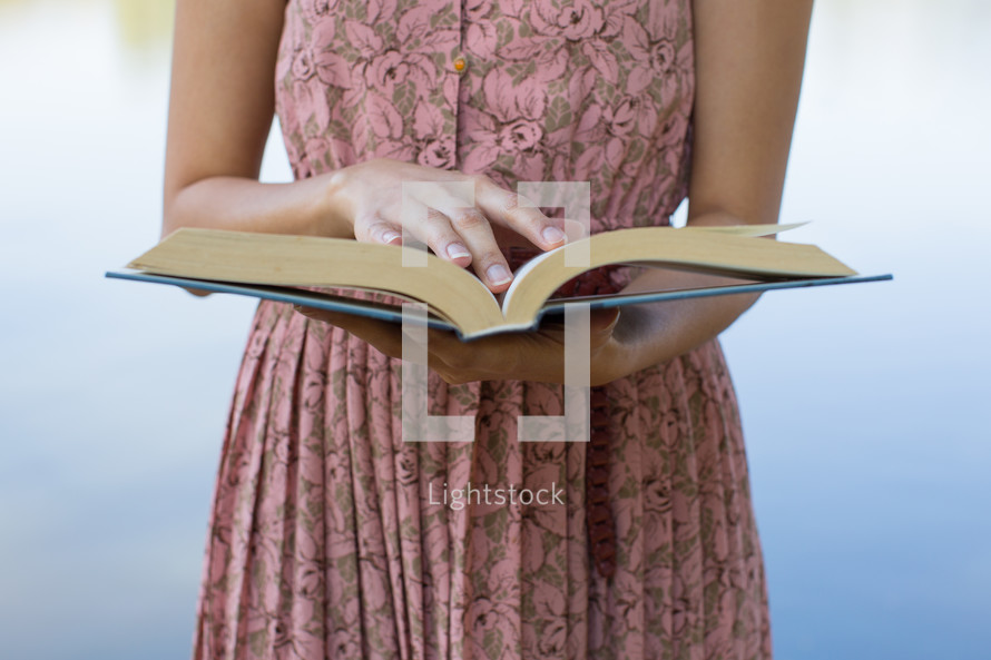 torso of a woman in a pink dress reading a book 