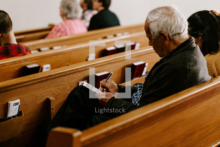 church visitor filling out an information card in a church pew 