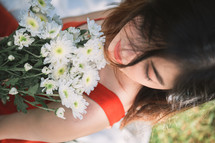 a woman in a red dress holding a bouquet of daisies 