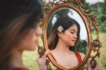 a woman looking in her reflection in a mirror 