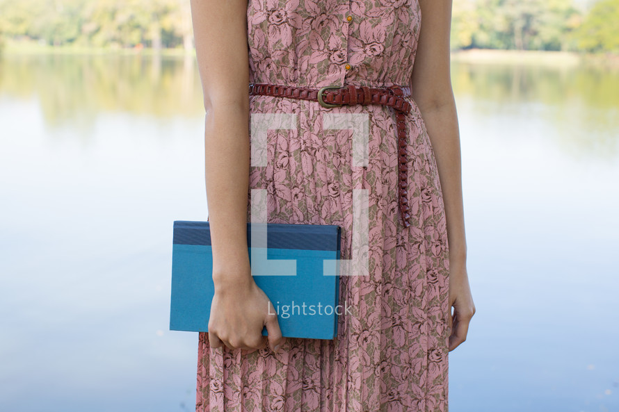 torso of a woman in a pink dress holding a Bible 