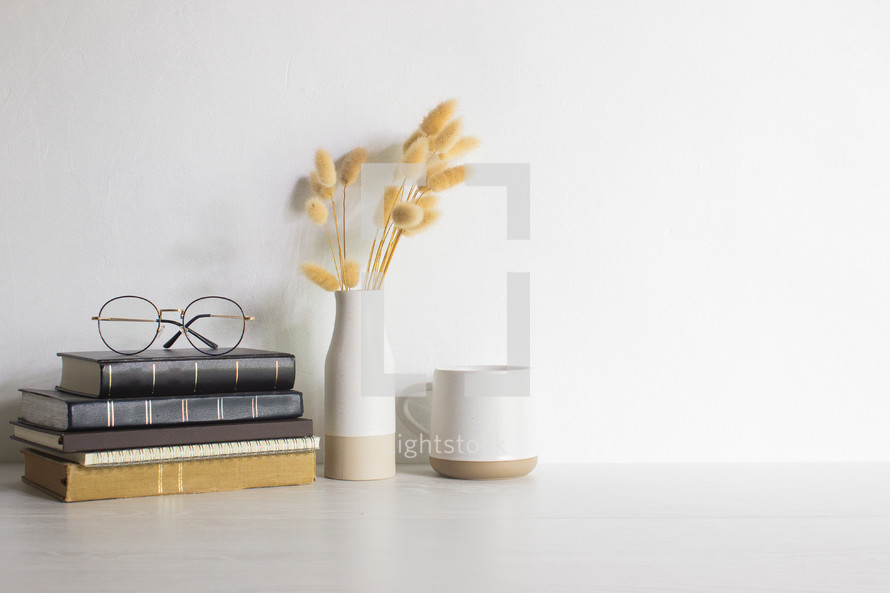 Minimal reading concept with books, reading glasses, flowers and coffee cups over wooden table. 