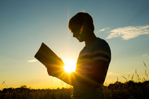 silhouette of a man reading a Bible 