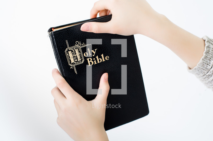 Child's hands holding a Bible.