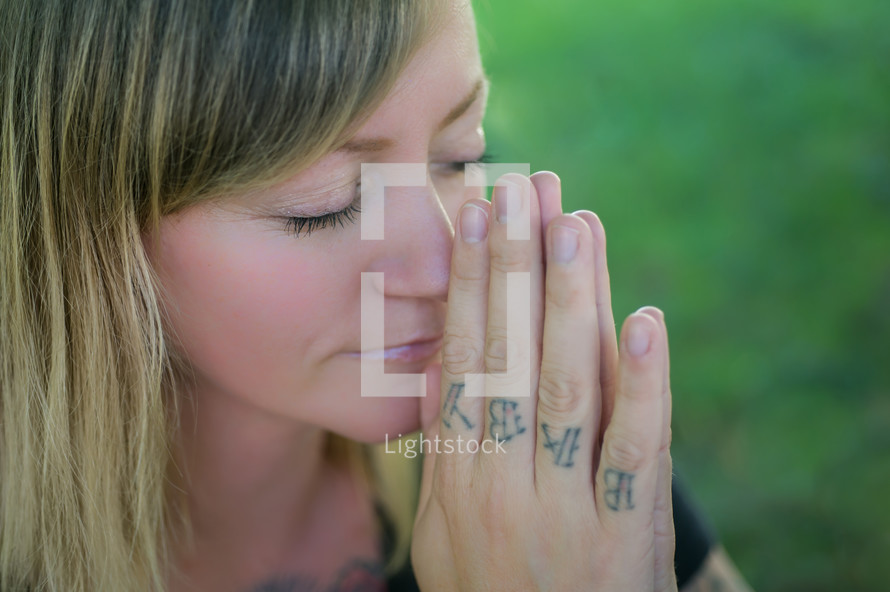 woman with tattooed hands praying 