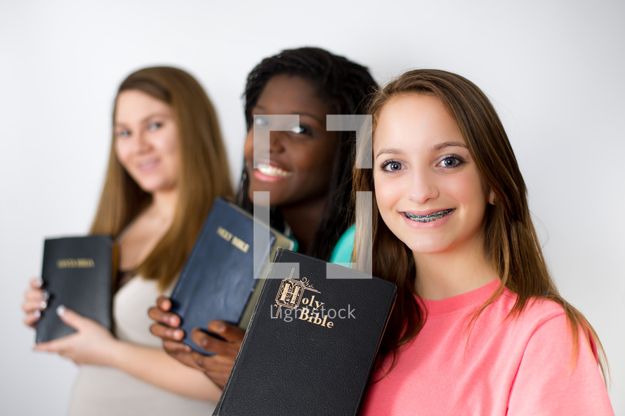 smiling teen girls holding Bibles