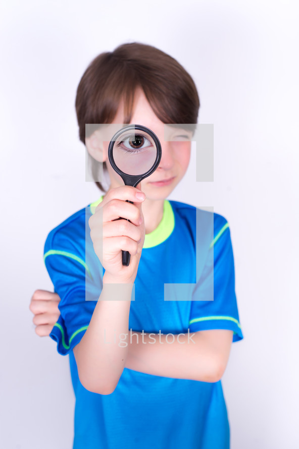 Boy with a magnifying glass to his eye.