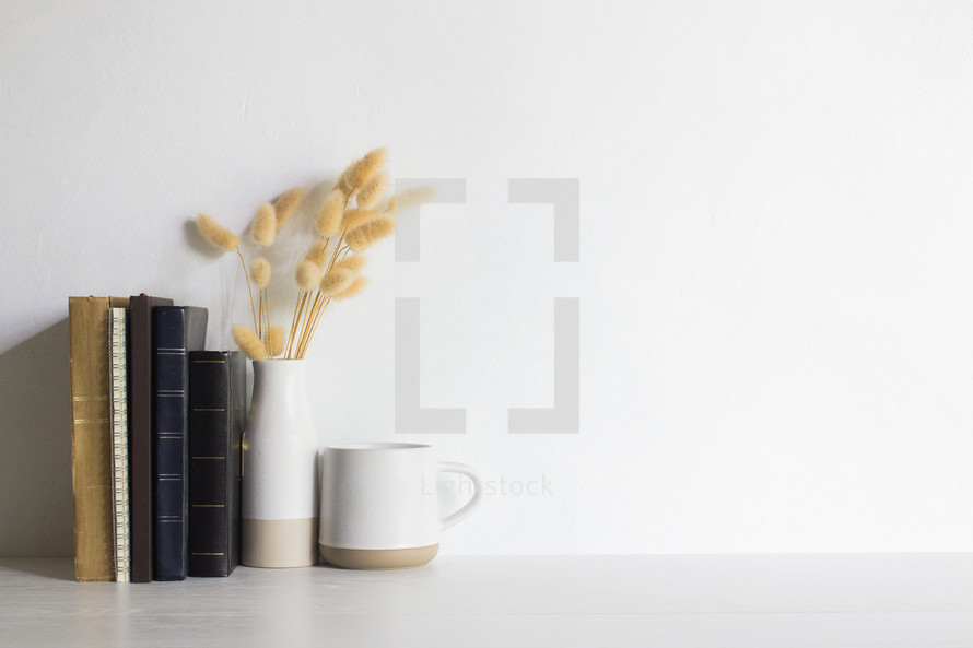 Minimal reading concept with books, coffee cups and flowers on wooden table. 