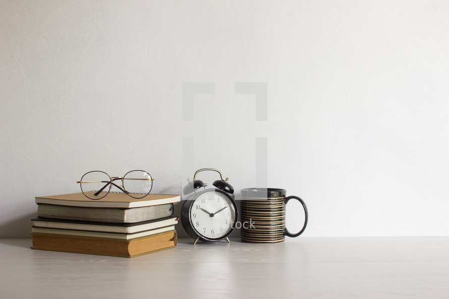 Reading concept with reading glasses, clock and coffee cups with light. 