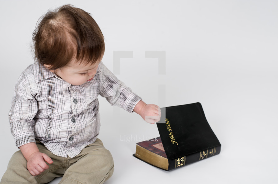 baby boy opening a Bible 