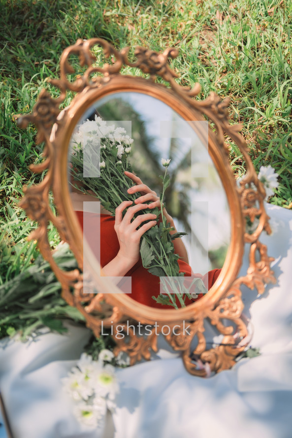 reflection in a mirror of a woman holding a bouquet of daisies 