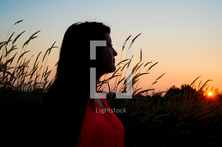 profile of a woman in a field at sunset 